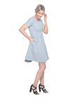 Petite model facing the side wearing grey with white pin striped, knee length dress, featuring rounded neckline, fitted bodice, pleated A-line skirt and pockets. Kaitlyn available in sizes 6-26