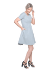 Petite model facing the side wearing grey with white pin striped, knee length dress, featuring rounded neckline, fitted bodice, pleated A-line skirt and pockets. Kaitlyn available in sizes 6-26