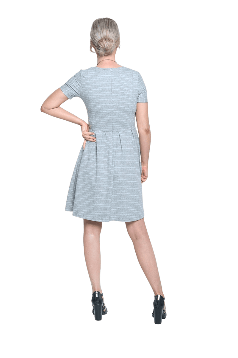 Petite model facing the back wearing grey with white pin striped, knee length dress, featuring rounded neckline, fitted bodice, pleated A-line skirt and pockets. Kaitlyn available in sizes 6-26