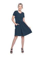 Petite model facing camera wearing navy with white pin striped, knee length dress, featuring rounded neckline, fitted bodice, pleated A-line skirt and pockets. Kaitlyn available in sizes 6-26