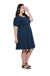 Curvy model facing the side wearing navy with white pin striped, knee length dress, featuring rounded neckline, fitted bodice, pleated A-line skirt and pockets. Kaitlyn available in sizes 6-26