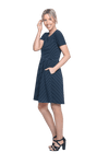 Petite model facing the side wearing navy with white pin striped, knee length dress, featuring rounded neckline, fitted bodice, pleated A-line skirt and pockets. Kaitlyn available in sizes 6-26