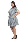 Curvy model facing the side wearing dusty blue with small pink floral, knee-length dress, featuring pockets, a rounded, frilled neckline, and a tiered skirt. Kirsty available in sizes 6-26