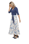 Petite model facing the side wearing maxi dress with blue mid sleeved crossover top attached to white skirt with blue and tan watercolour accents. Mai available in sizes 6-26