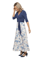 Petite model facing the side wearing maxi dress with blue mid sleeved crossover top attached to white skirt with blue and tan watercolour accents. Mai available in sizes 6-26