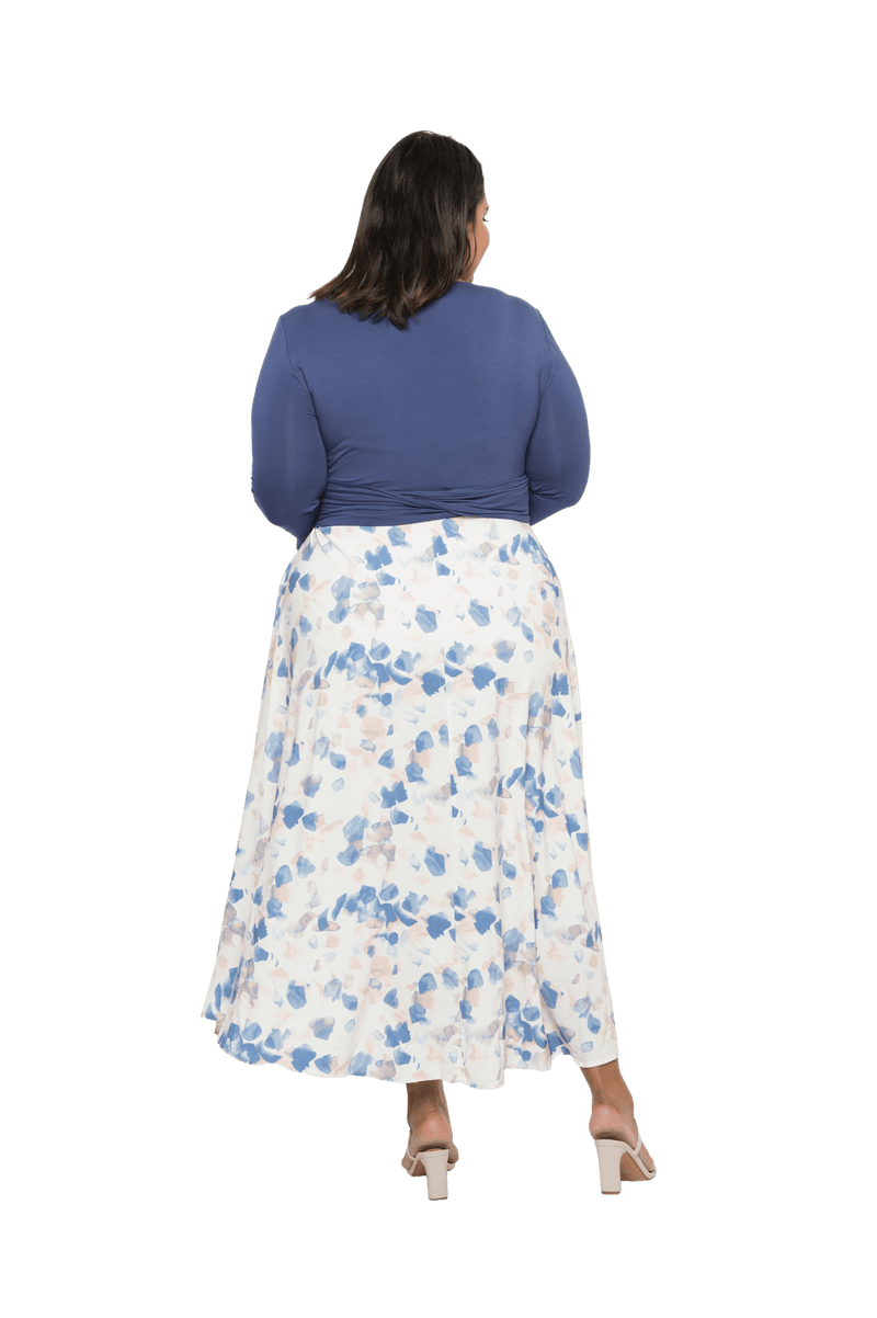 Curvy model facing the back wearing maxi dress with blue mid sleeved crossover top attached to white skirt with blue and tan watercolour accents. Mai available in sizes 6-26