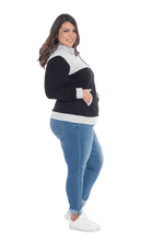 Curvy model facing the side wearing black hoodie with grey panel over chest, shoulders, and top of back, featuring front pocket, and grey highlights at pocket openings and sleeve cuffs. Olivia hoodie available in sizes 6-26