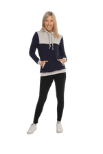 Petite model facing camera wearing navy hoodie with grey panel over chest, shoulders, and top of back, featuring front pocket, and grey highlights at pocket openings and sleeve cuffs. Olivia hoodie available in sizes 6-26