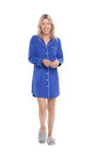 Petite model facing camera wearing royal blue button up, mid thigh length pyjama shirt, featuring fold over collar, scooped hemline, and white piping. Parker available in sizes 6-18