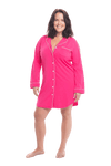 Brunette model facing camera wearing hot pink button up, mid thigh length pyjama shirt, featuring fold over collar, scooped hemline, and white piping. Parker available in sizes 6-18