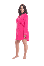 Brunette model facing the side wearing royal blue button up, mid thigh length pyjama shirt, featuring fold over collar, scooped hemline, and white piping. Parker available in sizes 6-18