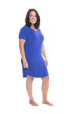 Brunette model facing the side wearing royal blue mid thigh length nightie, featuring rounded neckline, scooped hemline with short sleeves. Penny available in sizes 6-18