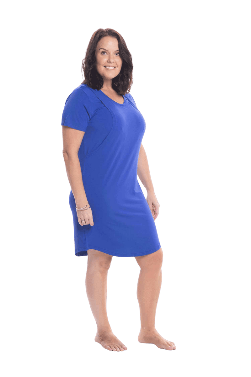 Brunette model facing the side wearing royal blue mid thigh length nightie, featuring rounded neckline, scooped hemline with short sleeves. Penny available in sizes 6-18