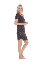 Petite model facing the side wearing black with small red rose patterned mid thigh length nightie, featuring rounded neckline, scooped hemline with short sleeves. Penny available in sizes 6-18