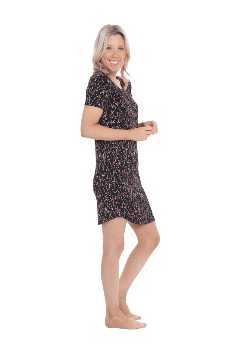 Petite model facing the side wearing black with small red rose patterned mid thigh length nightie, featuring rounded neckline, scooped hemline with short sleeves. Penny available in sizes 6-18