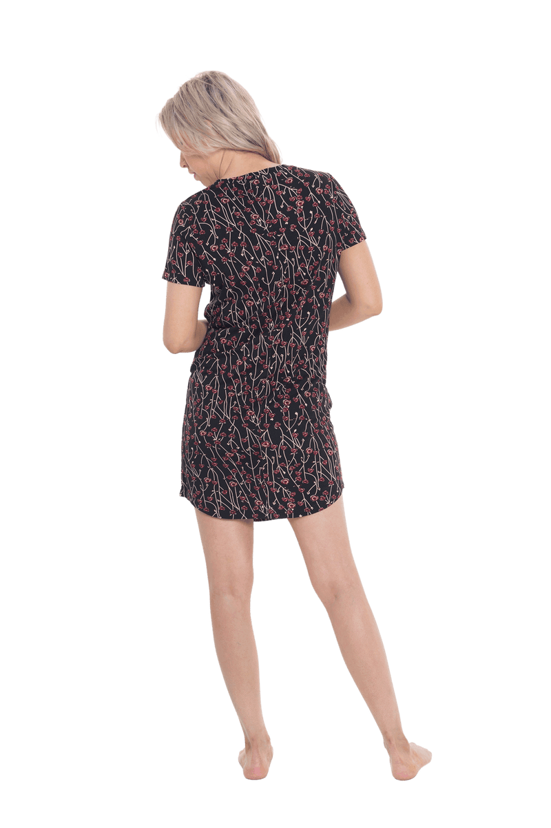 Petite model facing the back wearing black with small red rose patterned mid thigh length nightie, featuring rounded neckline, scooped hemline with short sleeves. Penny available in sizes 6-18