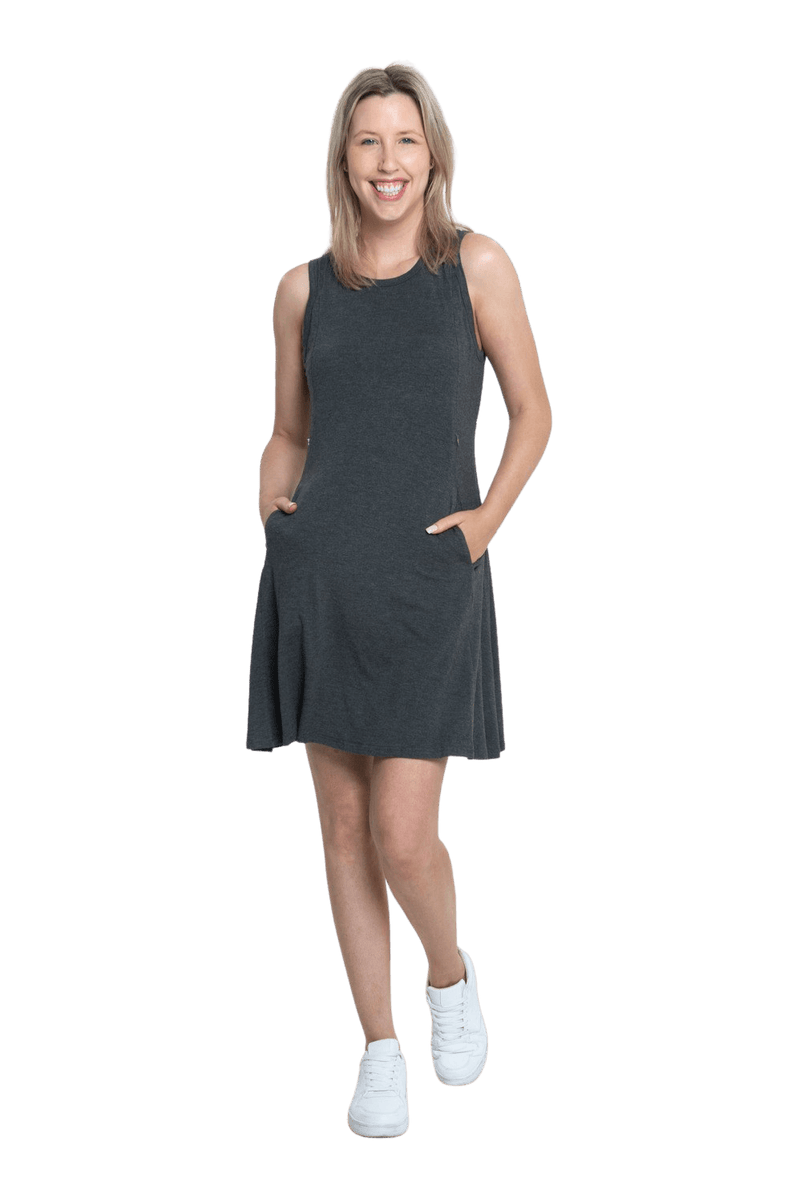 Petite model facing camera wearing charcoal grey mid thigh length dress, featuring rounded neckline, pockets and a waist sash tied at the back. Peyton available in sizes 6-26