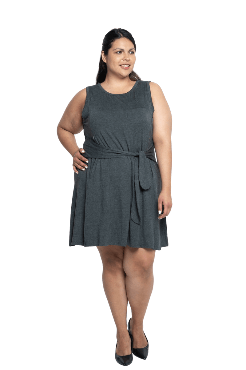 Curvy model facing camera wearing charcoal grey mid thigh length dress, featuring rounded neckline, pockets and a waist sash tied at the front. Peyton available in sizes 6-26