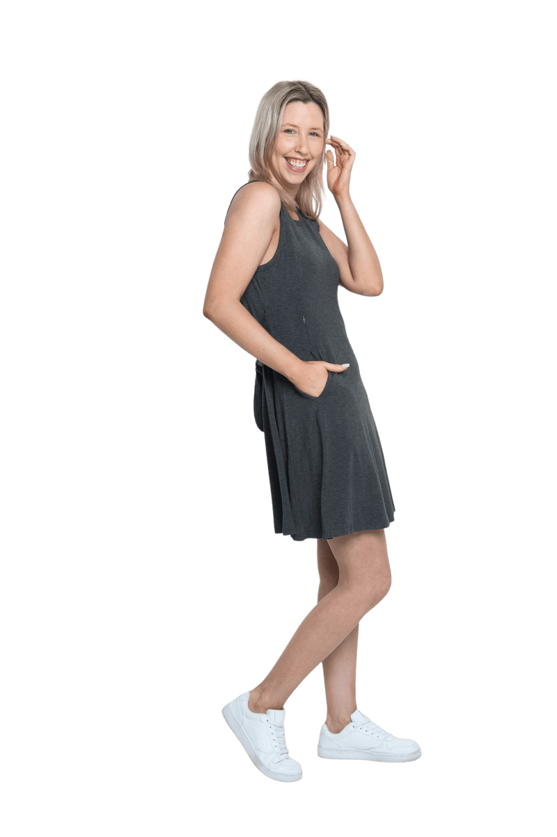 Petite model facing the side wearing charcoal grey mid thigh length dress, featuring rounded neckline, pockets and a waist sash tied at the back. Peyton available in sizes 6-26