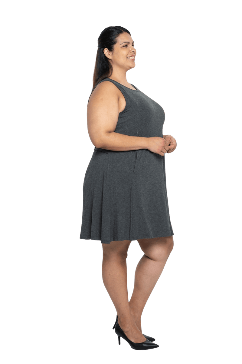 Curvy model facing the side wearing charcoal grey mid thigh length dress, featuring rounded neckline, pockets and a waist sash tied at the back. Peyton available in sizes 6-26