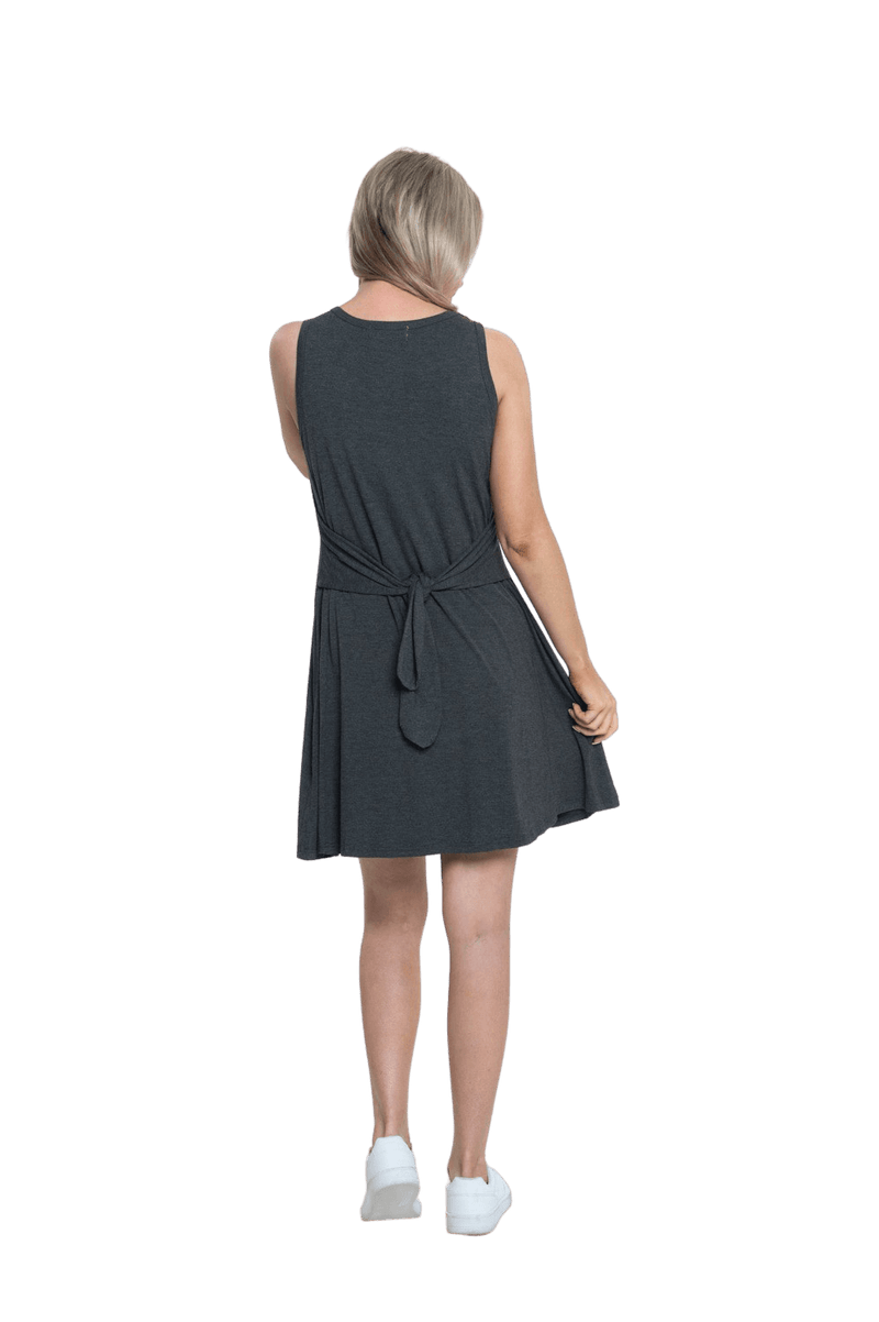 Petite model facing the back wearing charcoal grey mid thigh length dress, featuring rounded neckline, pockets and a waist sash tied at the back. Peyton available in sizes 6-26
