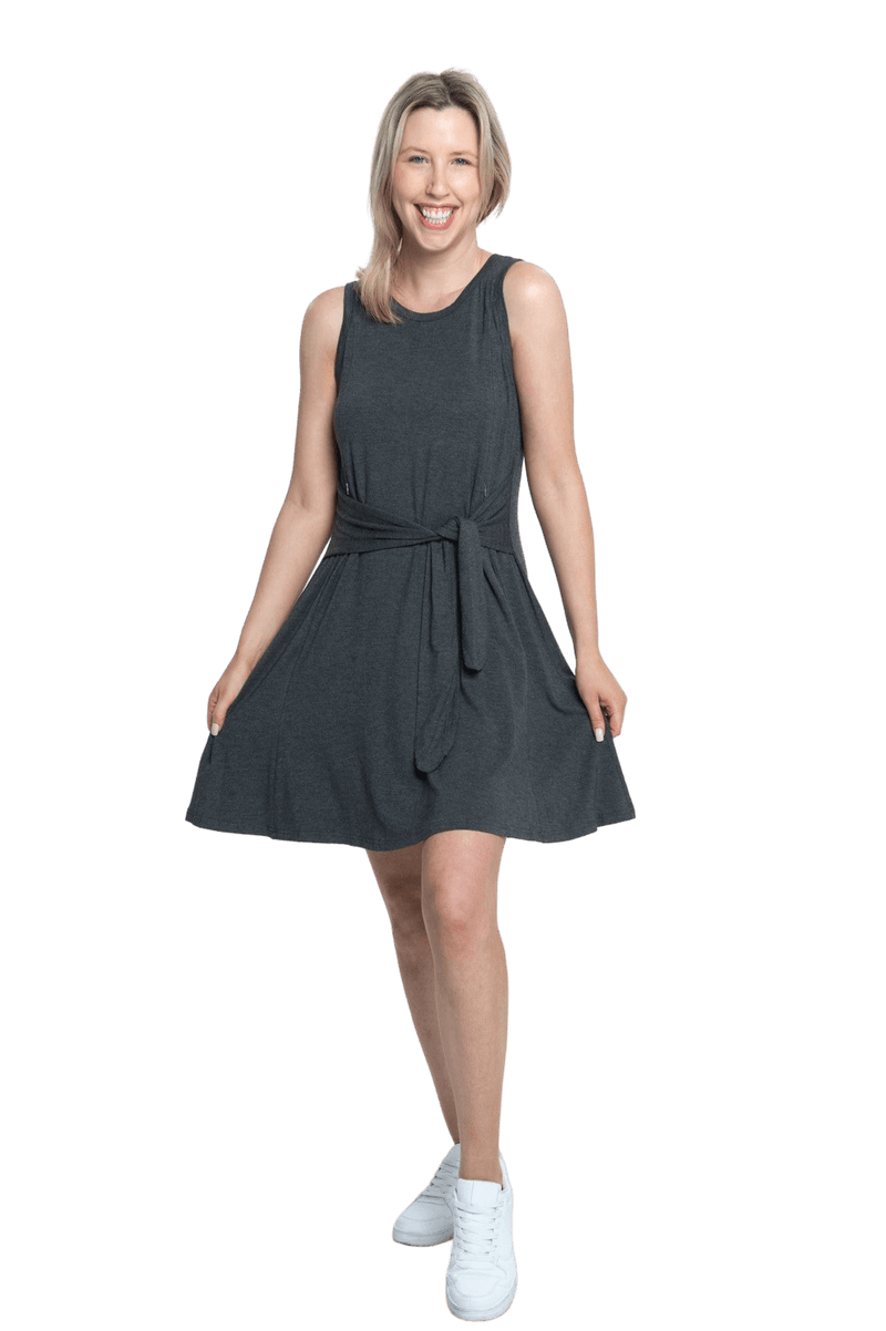 Petite model facing camera wearing charcoal grey mid thigh length dress, featuring rounded neckline, pockets and a waist sash tied at the front. Peyton available in sizes 6-26