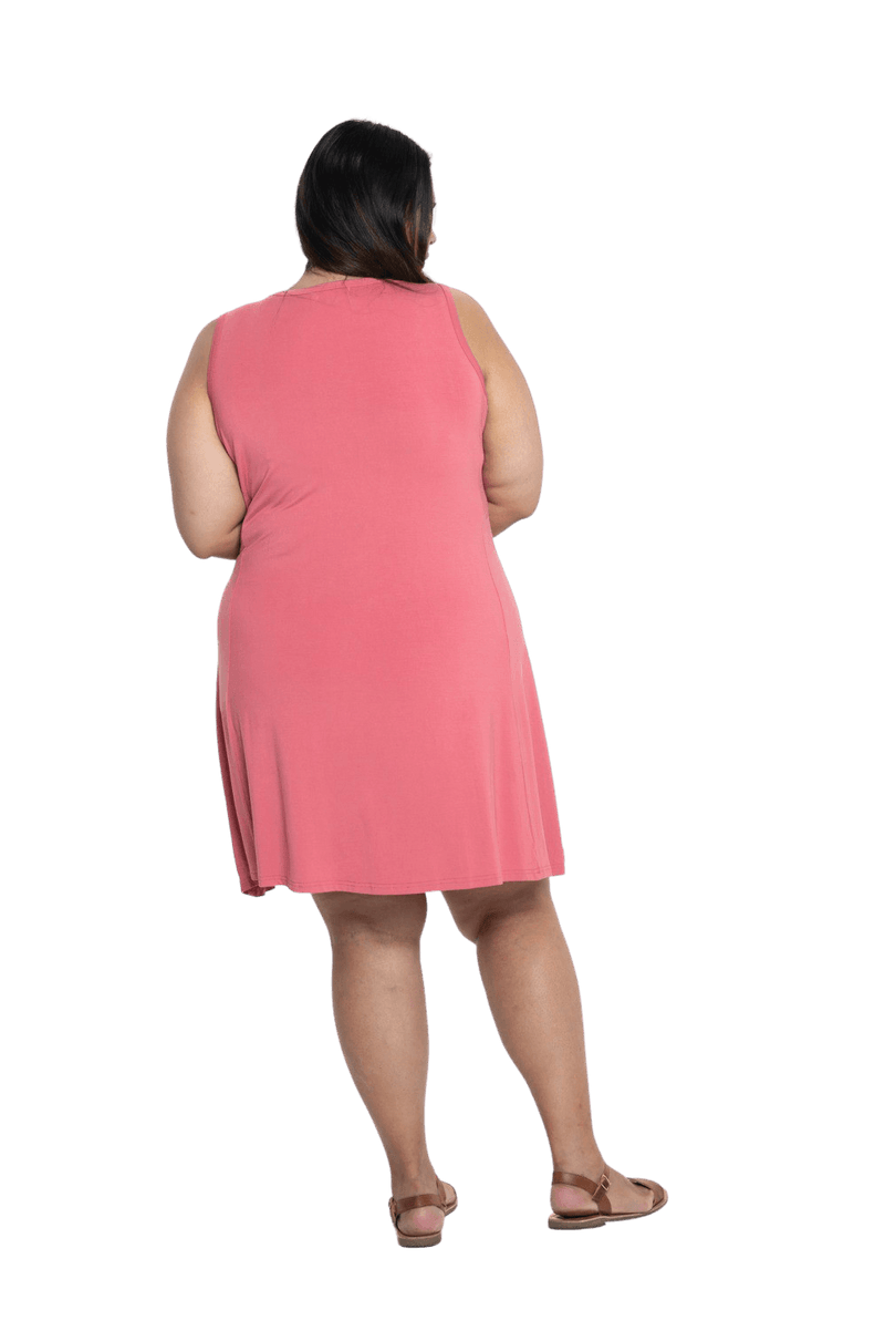Curvy model facing the back wearing dusty pink mid thigh length dress, featuring rounded neckline, pockets and a waist sash tied at the front. Peyton available in sizes 6-26