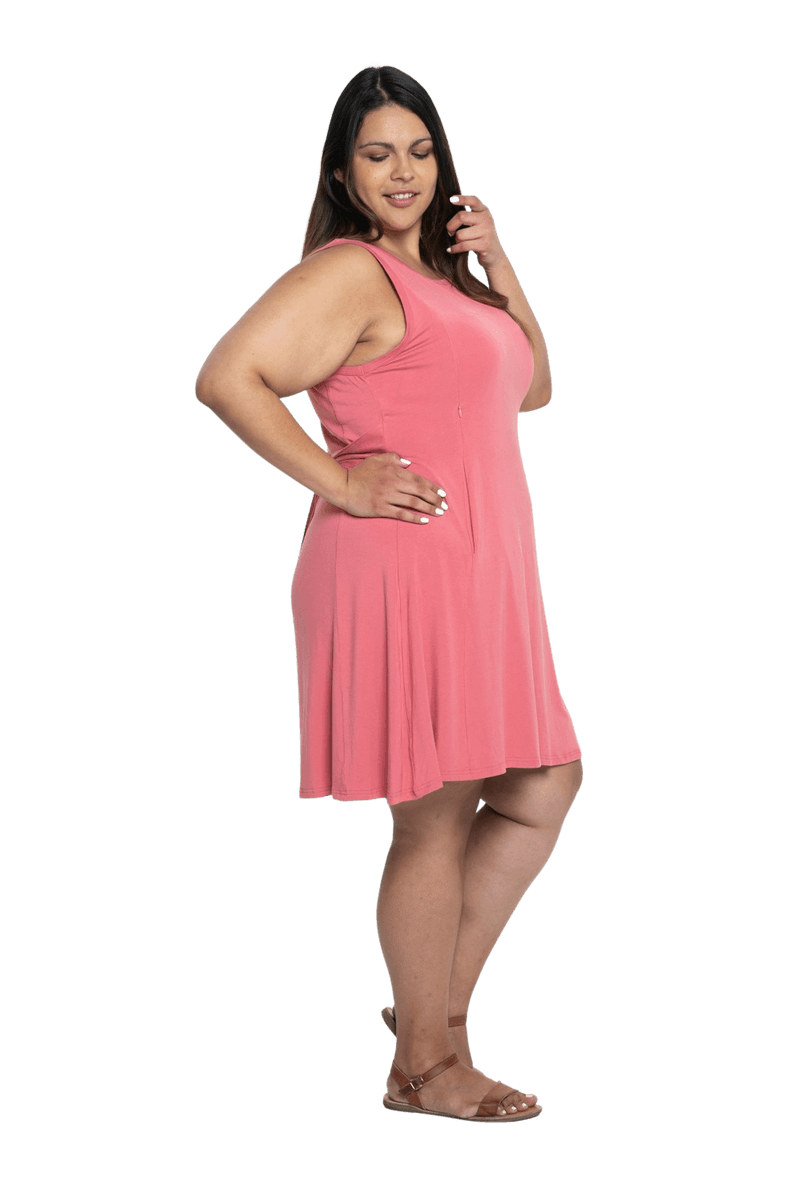 Curvy model facing the side wearing dusty pink mid thigh length dress, featuring rounded neckline, pockets and a waist sash tied at the back. Peyton available in sizes 6-26
