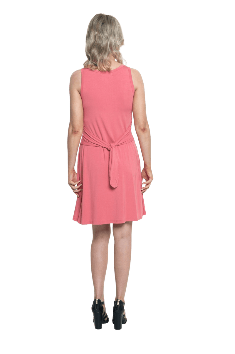 Petite model facing the back wearing dusty pink mid thigh length dress, featuring rounded neckline, pockets and a waist sash tied at the back. Peyton available in sizes 6-26