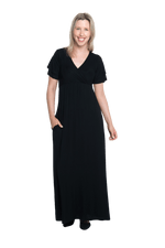 Petite model facing camera wearing black maxi dress, featuring crossover V-neck, double layer detailed sleeves, pockets and a beautiful Grecian flowing silhouette. Phoebe available in sizes 6-26