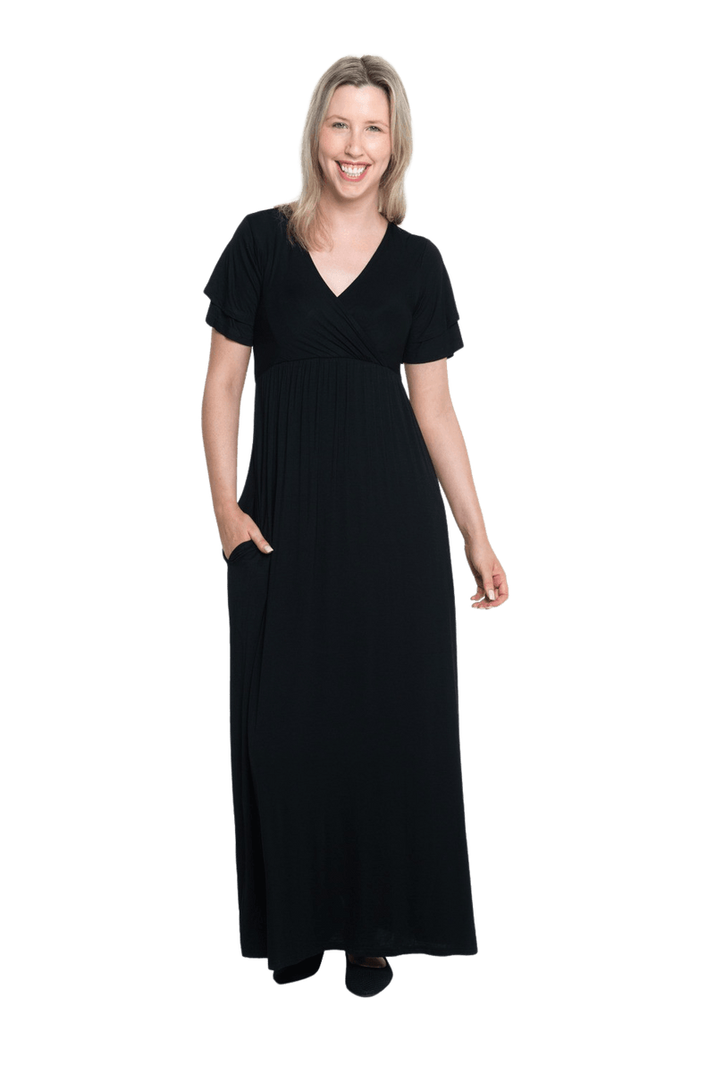 Petite model facing camera wearing black maxi dress, featuring crossover V-neck, double layer detailed sleeves, pockets and a beautiful Grecian flowing silhouette. Phoebe available in sizes 6-26