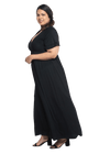 Curvy model facing the side wearing black maxi dress, featuring crossover V-neck, double layer detailed sleeves, pockets and a beautiful Grecian flowing silhouette. Phoebe available in sizes 6-26