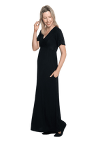 Petite model facing the side wearing black maxi dress, featuring crossover V-neck, double layer detailed sleeves, pockets and a beautiful Grecian flowing silhouette. Phoebe available in sizes 6-26