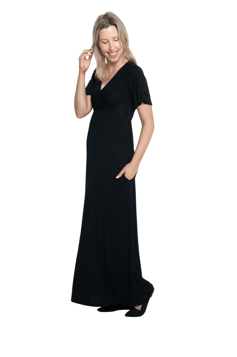 Petite model facing the side wearing black maxi dress, featuring crossover V-neck, double layer detailed sleeves, pockets and a beautiful Grecian flowing silhouette. Phoebe available in sizes 6-26