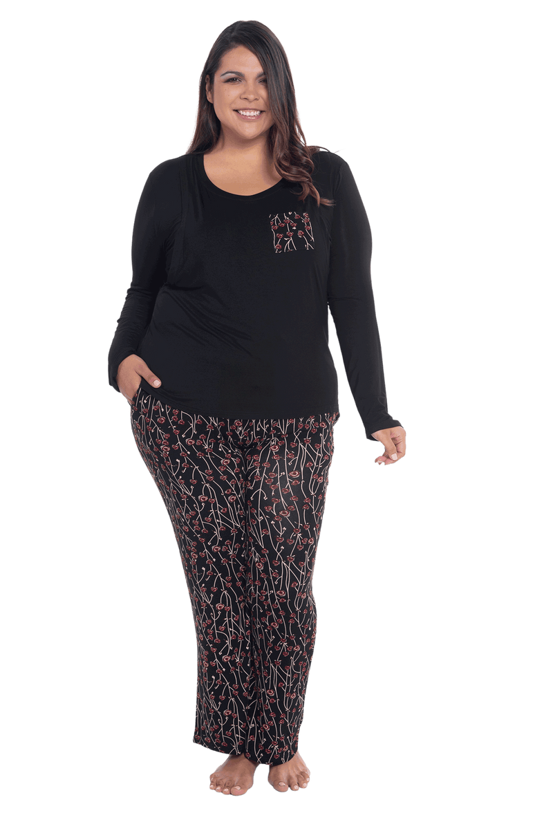 Curvy model facing camera wearing long sleeved pyjamas with pants. Top is black with contrast breast pocket matching pants. Pants are black with small red rose pattern, featuring pockets, and elasticated waist with pull tie. Piper available in sizes 6-26