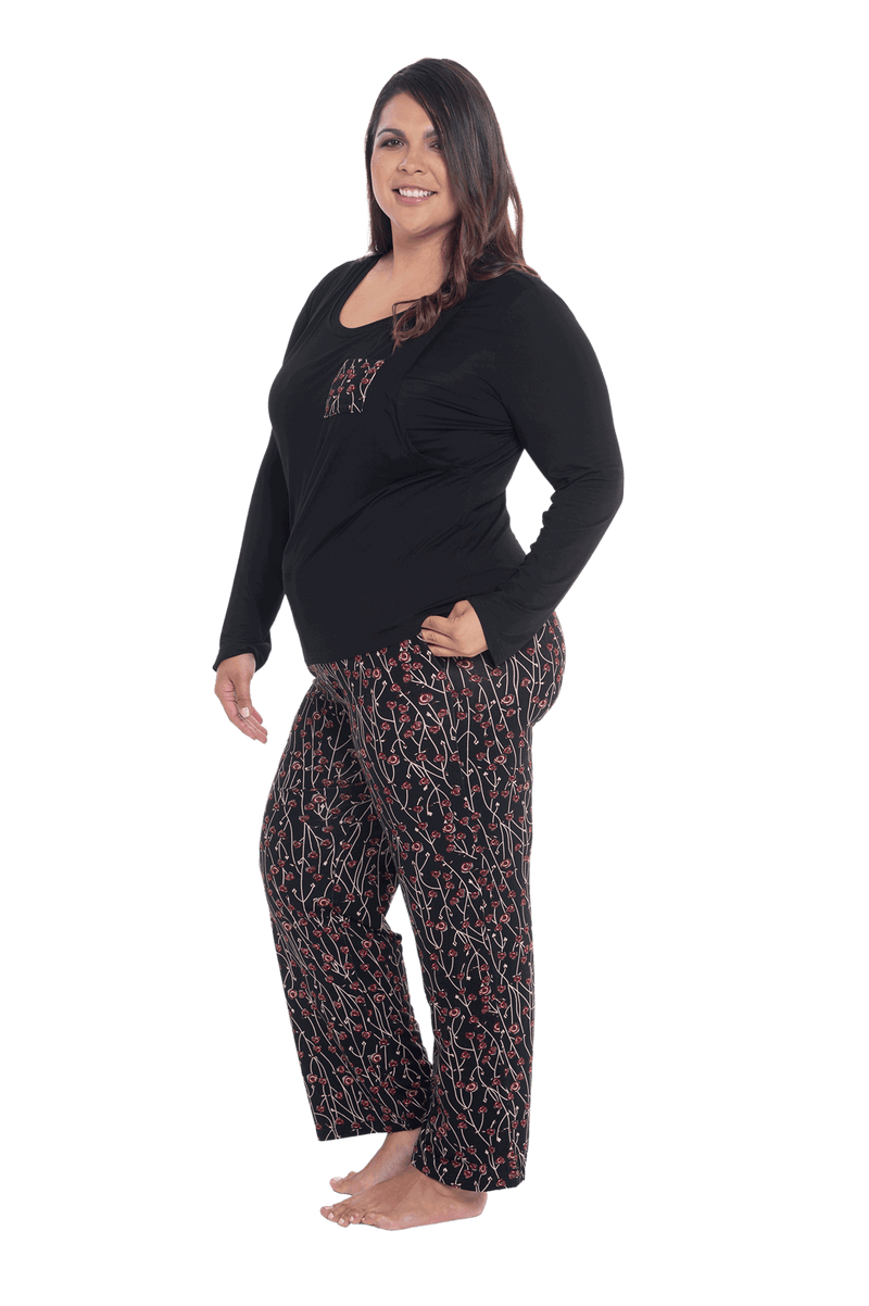 Curvy model facing the side wearing long sleeved pyjamas with pants. Top is black with contrast breast pocket matching pants. Pants are black with small red rose pattern, featuring pockets, and elasticated waist with pull tie. Piper available in sizes 6-26