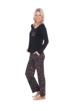 Petite model facing the side wearing long sleeved pyjamas with pants. Top is black with contrast breast pocket matching pants. Pants are black with small red rose pattern, featuring pockets, and elasticated waist with pull tie. Piper available in sizes 6-26