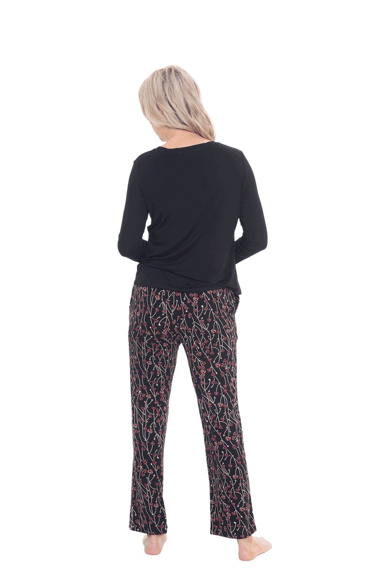 Petite model facing the back wearing long sleeved pyjamas with pants. Top is black with contrast breast pocket matching pants. Pants are black with small red rose pattern, featuring pockets, and elasticated waist with pull tie. Piper available in sizes 6-26