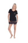 Petite model facing the camera wearing short sleeved pyjamas with shorts. Top is black with contrast breast pocket matching shorts. Shorts are black with small red rose pattern, featuring pockets, and elasticated waist with pull tie. Poppy available in sizes 6-26