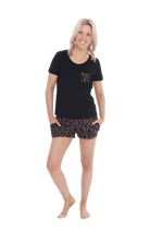 Petite model facing the camera wearing short sleeved pyjamas with shorts. Top is black with contrast breast pocket matching shorts. Shorts are black with small red rose pattern, featuring pockets, and elasticated waist with pull tie. Poppy available in sizes 6-26