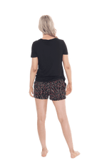 Petite model facing the back wearing short sleeved pyjamas with shorts. Top is black with contrast breast pocket matching shorts. Shorts are black with small red rose pattern, featuring pockets, and elasticated waist with pull tie. Poppy available in sizes 6-26