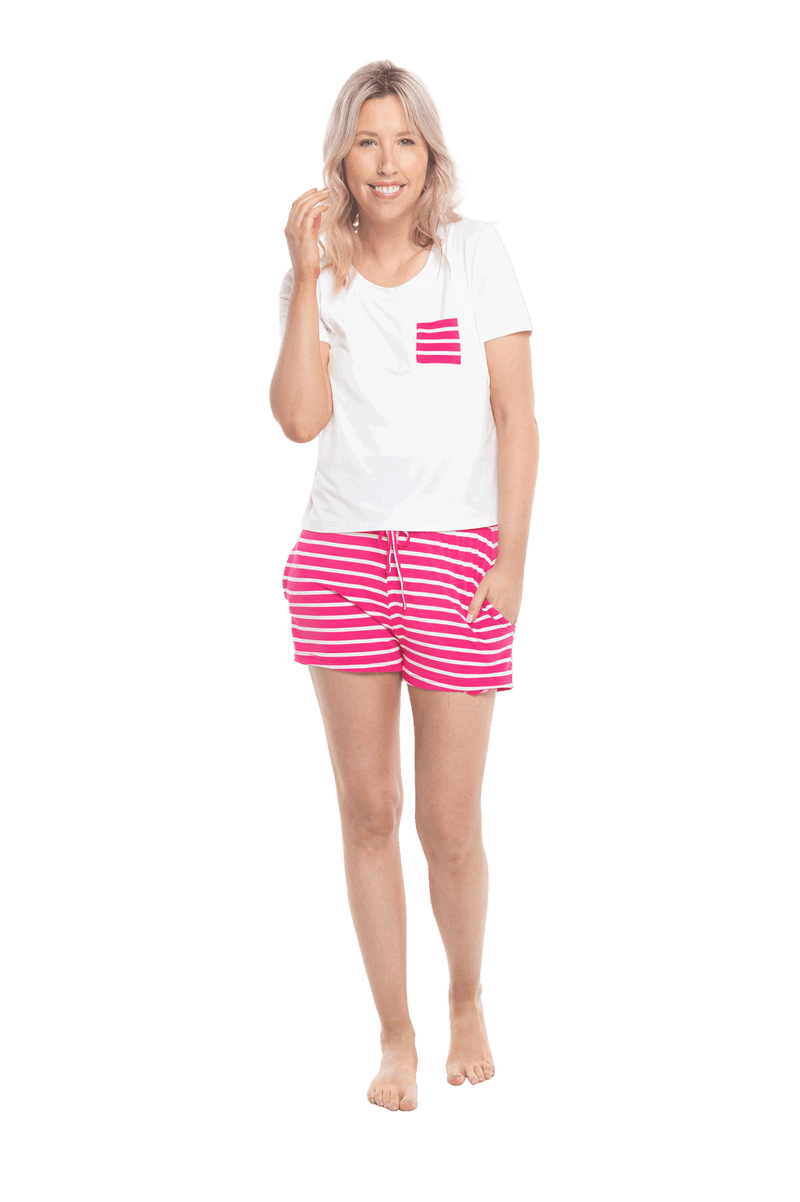 Petite model facing the camera wearing short sleeved pyjamas with shorts. Top is white with contrast breast pocket matching shorts. Shorts are hot pink and white stripe, featuring pockets, and elasticated waist with pull tie. Poppy available in sizes 6-18