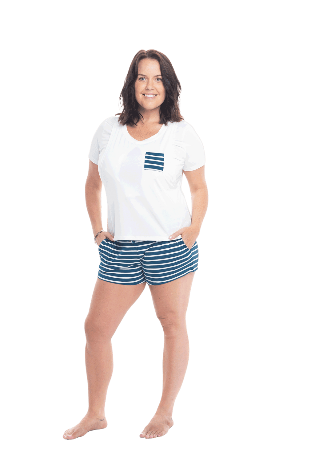 Brunette model facing the camera wearing short sleeved pyjamas with shorts. Top is white with contrast breast pocket matching shorts. Shorts are teal and white stripe, featuring pockets, and elasticated waist with pull tie. Poppy available in sizes 6-18