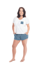 Brunette model facing the camera wearing short sleeved pyjamas with shorts. Top is white with contrast breast pocket matching shorts. Shorts are teal and white stripe, featuring pockets, and elasticated waist with pull tie. Poppy available in sizes 6-18