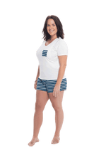 Brunette model facing the camera wearing short sleeved pyjamas with shorts. Top is white with contrast breast pocket matching shorts. Shorts are teal and white stripe, featuring pockets, and elasticated waist with pull tie. Poppy available in sizes 6-18