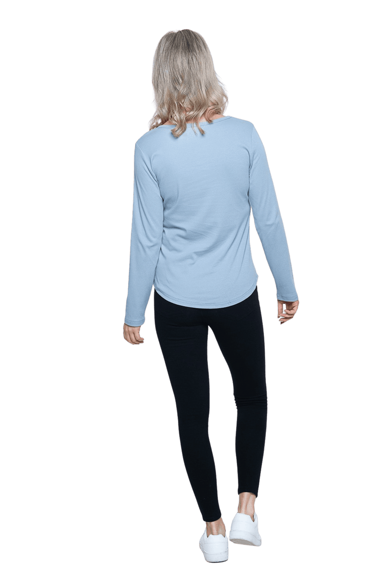 Petite model facing the back wearing dusty blue long sleeved top, featuring soft V-neck and a scooped hem. Reese available in sizes 6-26