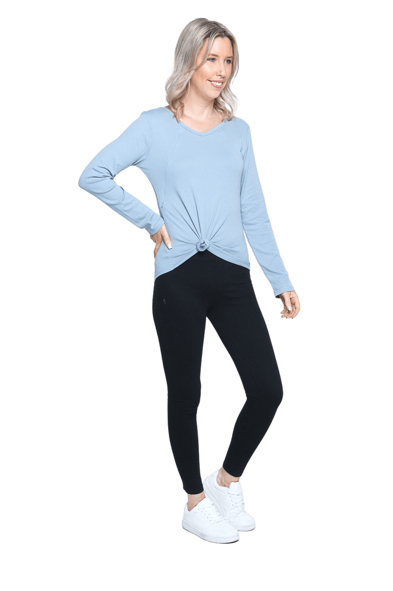 Petite model facing the side wearing dusty blue long sleeved top tied up, featuring soft V-neck and a scooped hem. Reese available in sizes 6-26
