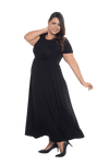 Curvy model facing the side wearing black maxi dress, featuring  rounded neckline, and a gently fitted bodice, gathering above the waist. Riley available in sizes 6-26