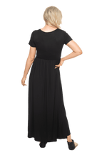 Petite model facing the back wearing black maxi dress, featuring  rounded neckline, and a gently fitted bodice, gathering above the waist. Riley available in sizes 6-26