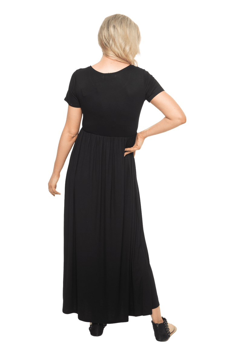 Petite model facing the back wearing black maxi dress, featuring  rounded neckline, and a gently fitted bodice, gathering above the waist. Riley available in sizes 6-26